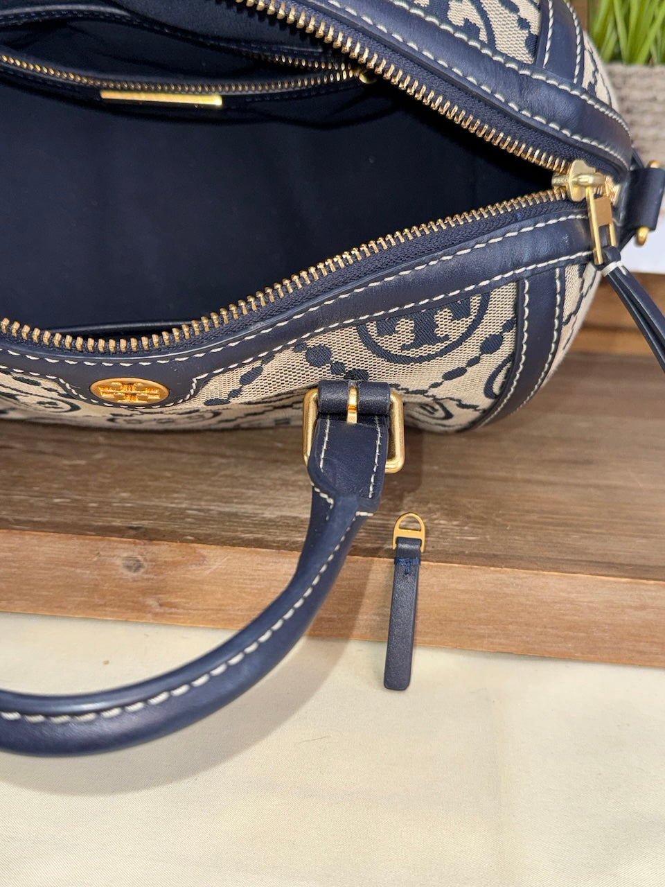 Navy blue handbag with patterned strap on a wooden surface