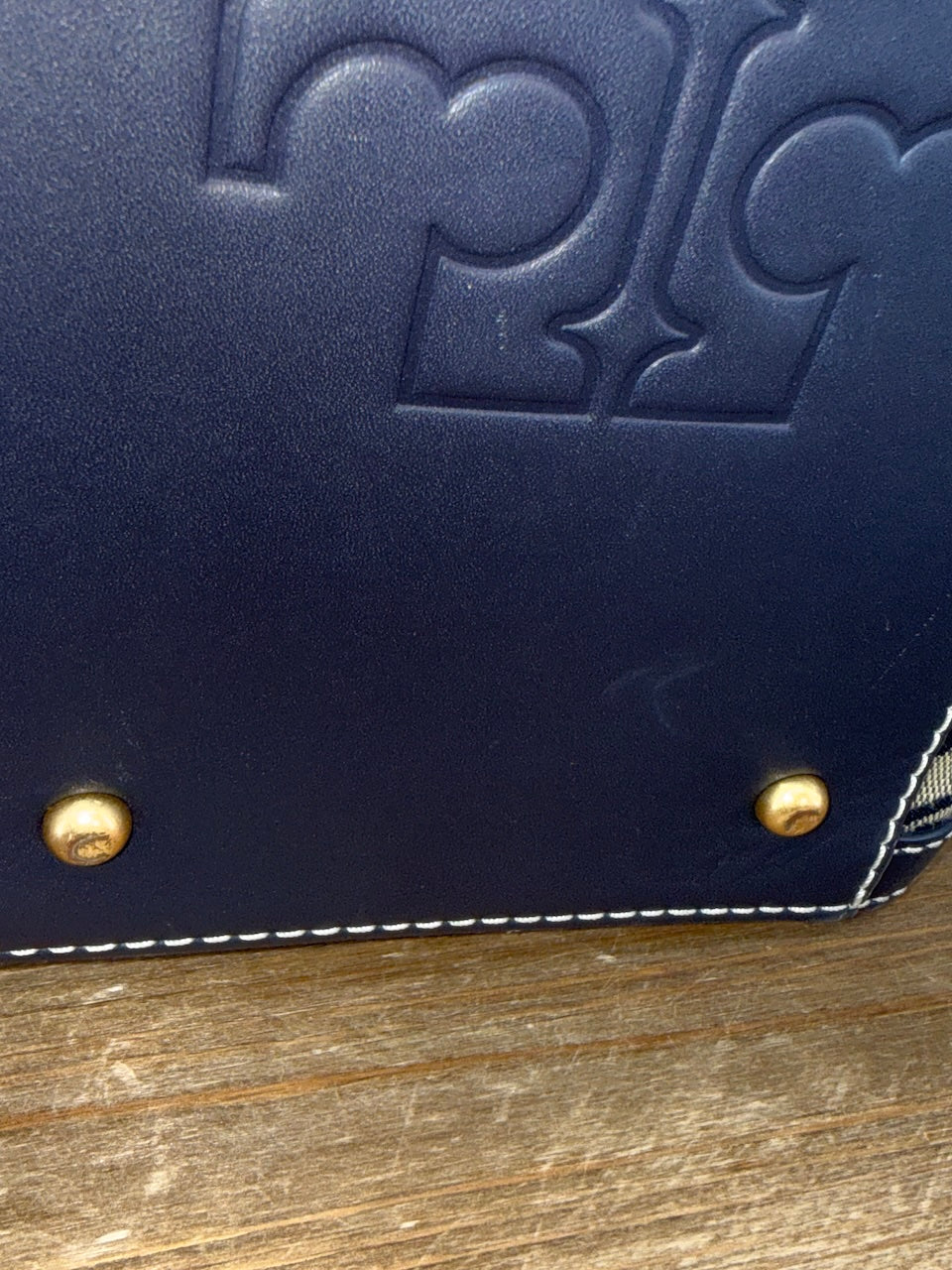 Navy blue leather wallet with gold studs on a wooden surface