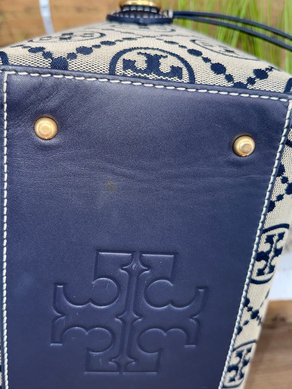 Close-up of a blue handbag with a patterned strap and visible brand logo.