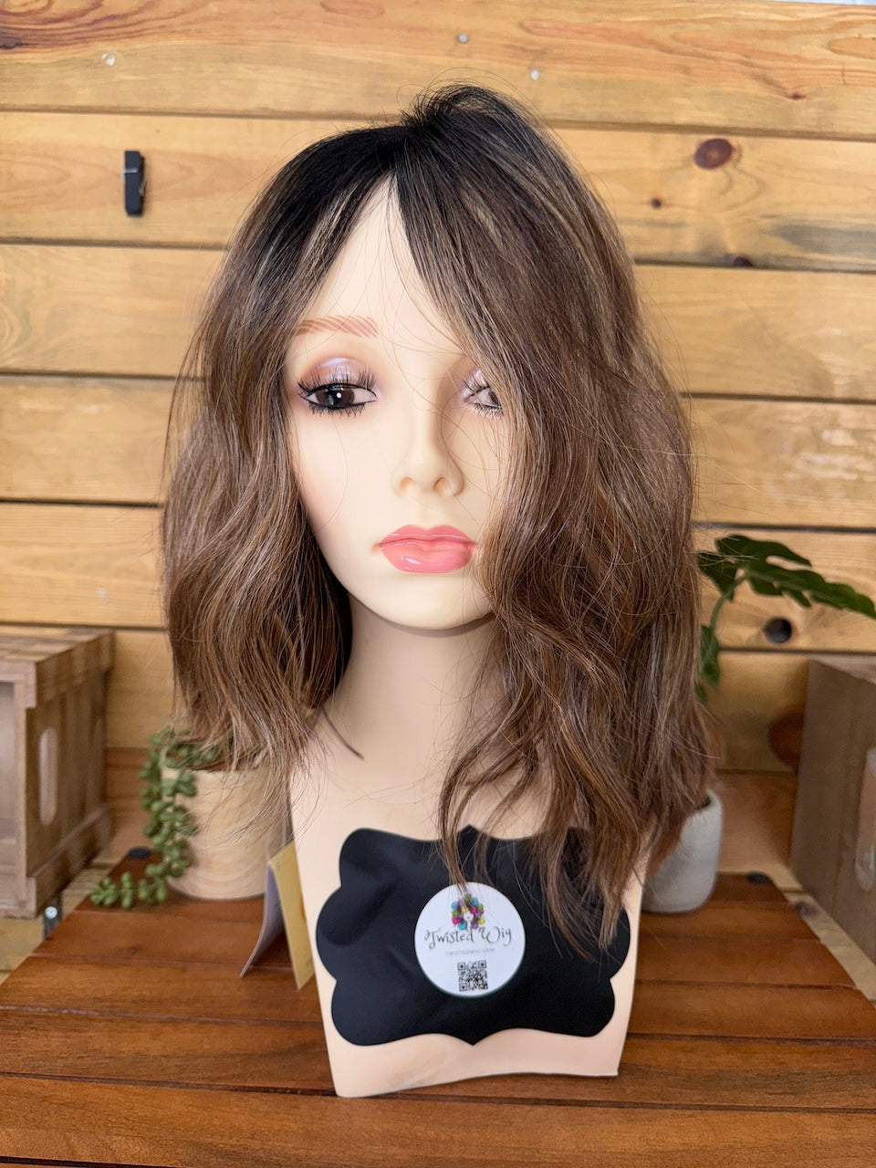 Mannequin head with a brown wig on a wooden background