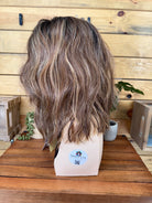 Brown wig on a mannequin head with a wooden background