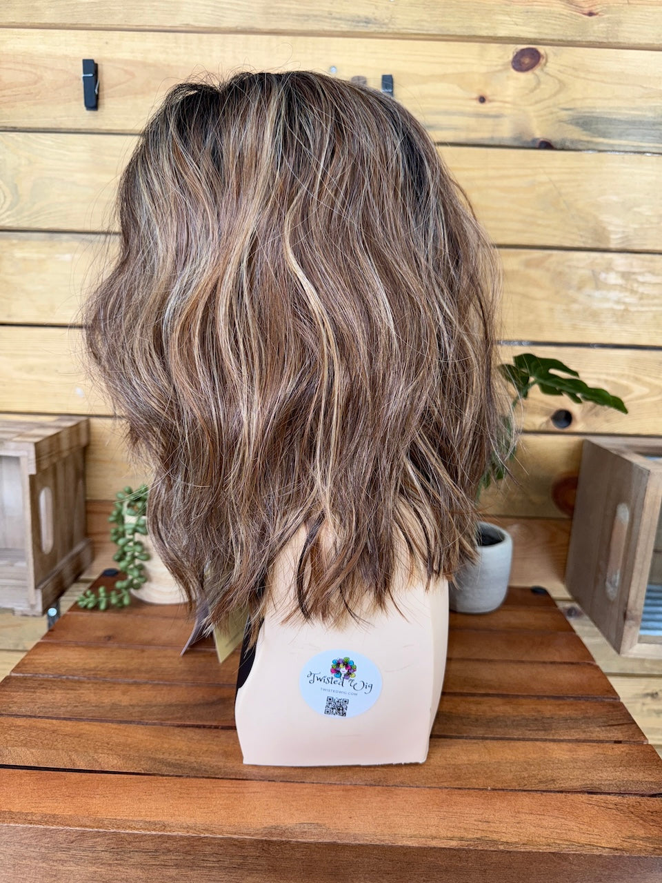 Brown wig on a mannequin head with a wooden background
