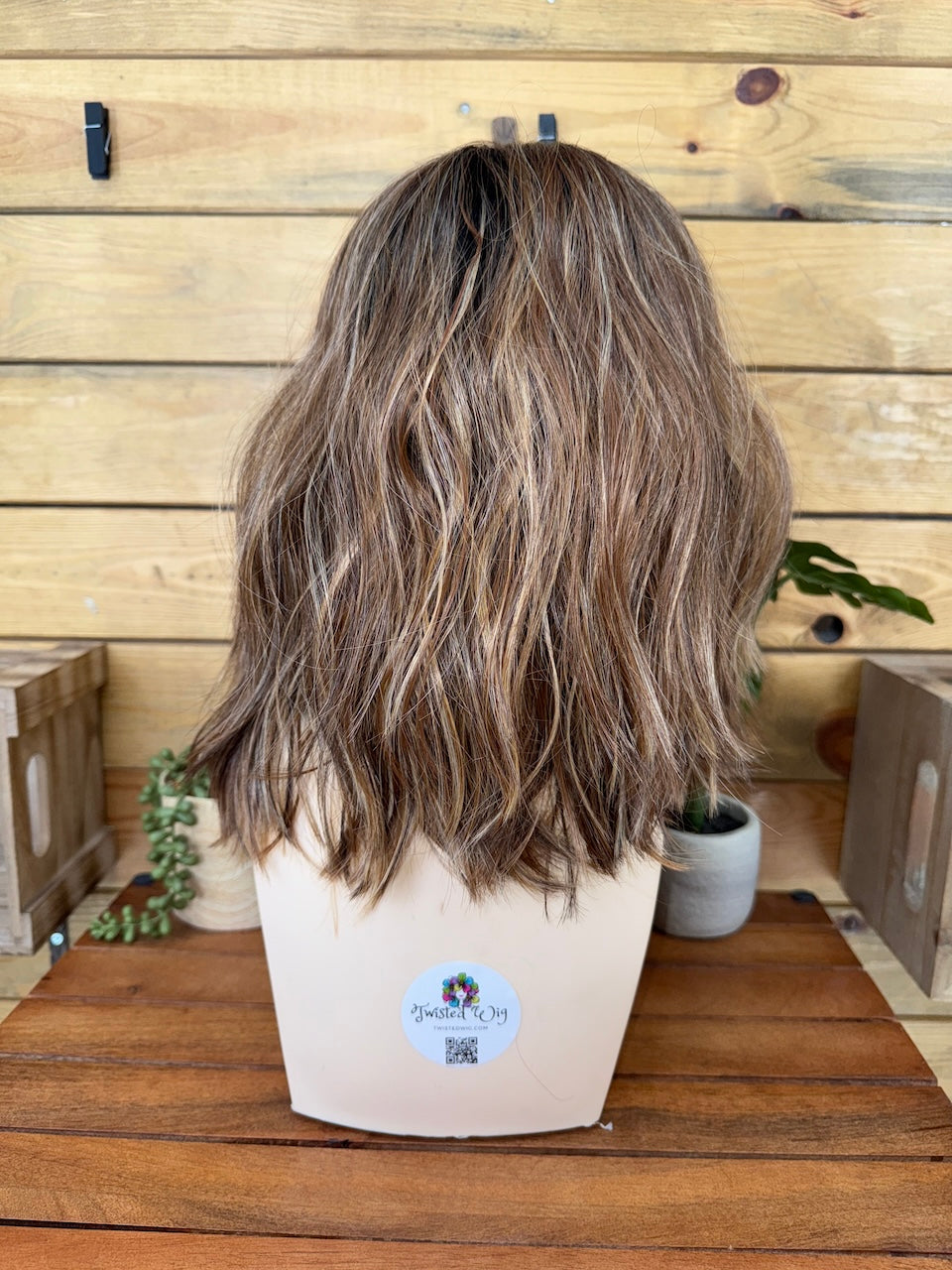 Brown wig on a mannequin head with a wooden background