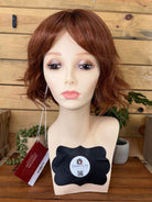 Mannequin head with brown wig on a wooden stand with a blurred background