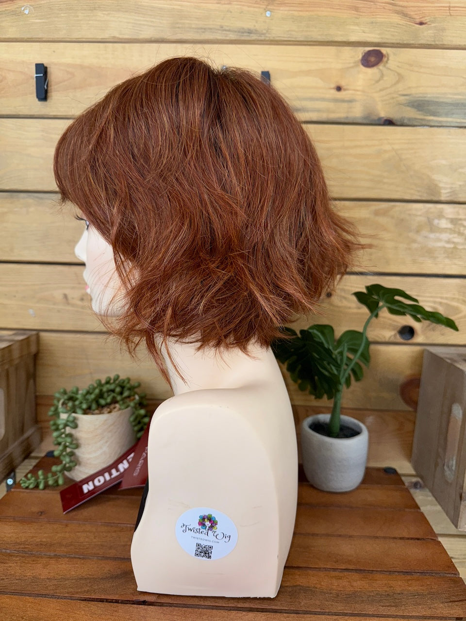 Brown wig on a mannequin head with a wooden background