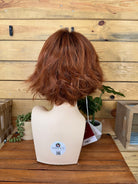 Brown wig on a mannequin head against a wooden background