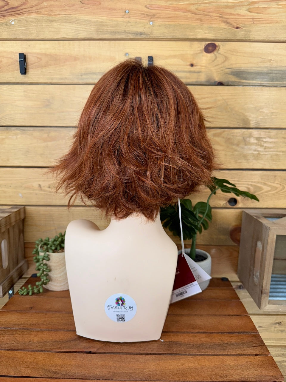 Brown wig on a mannequin head against a wooden background