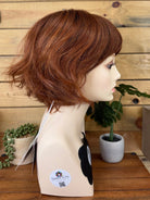 Mannequin head with a brown wig against a wooden background