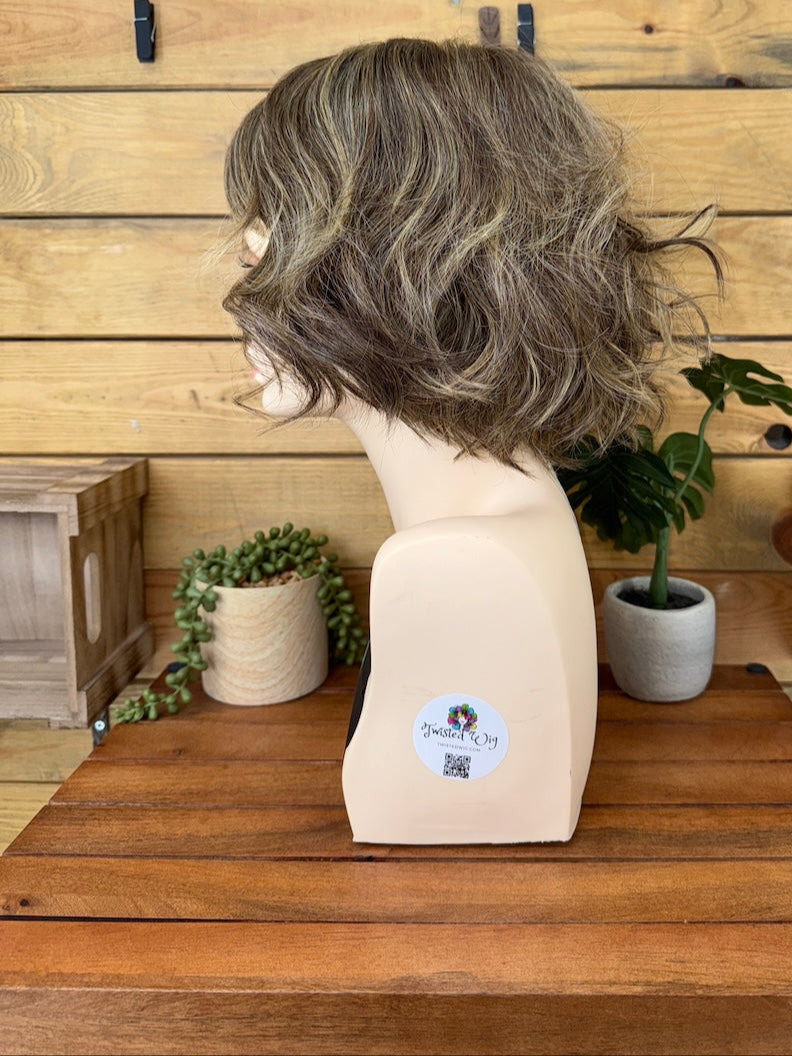 Mannequin head with a gray wig on a wooden surface with a wooden wall background