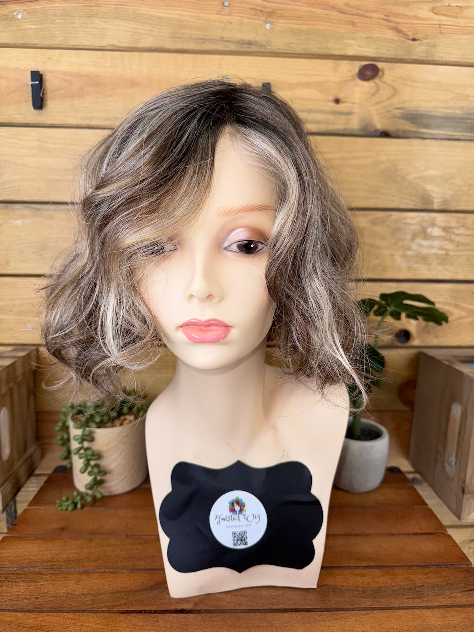 Mannequin head with a gray wig on a wooden background
