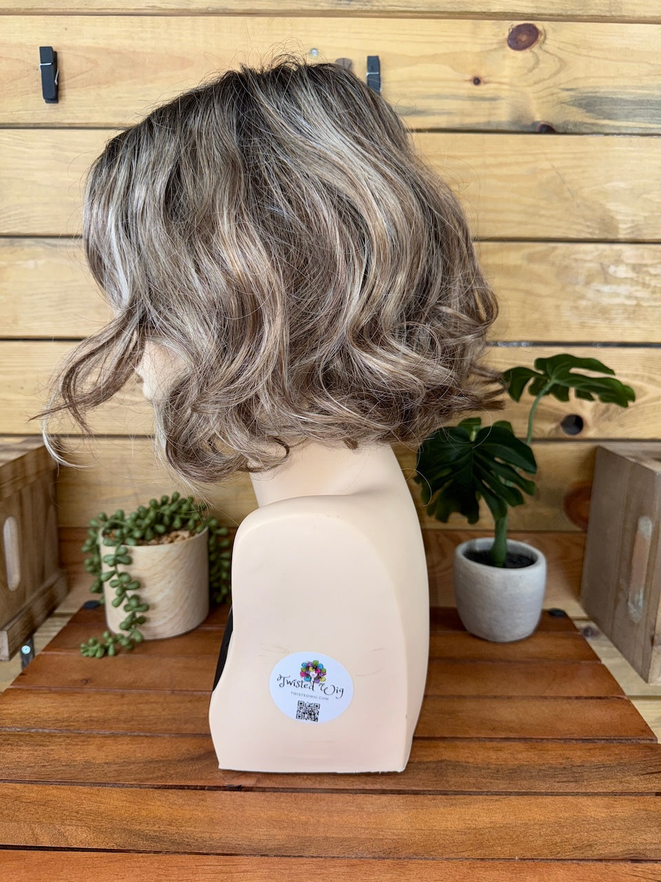 Gray wig on a mannequin head with a wooden background