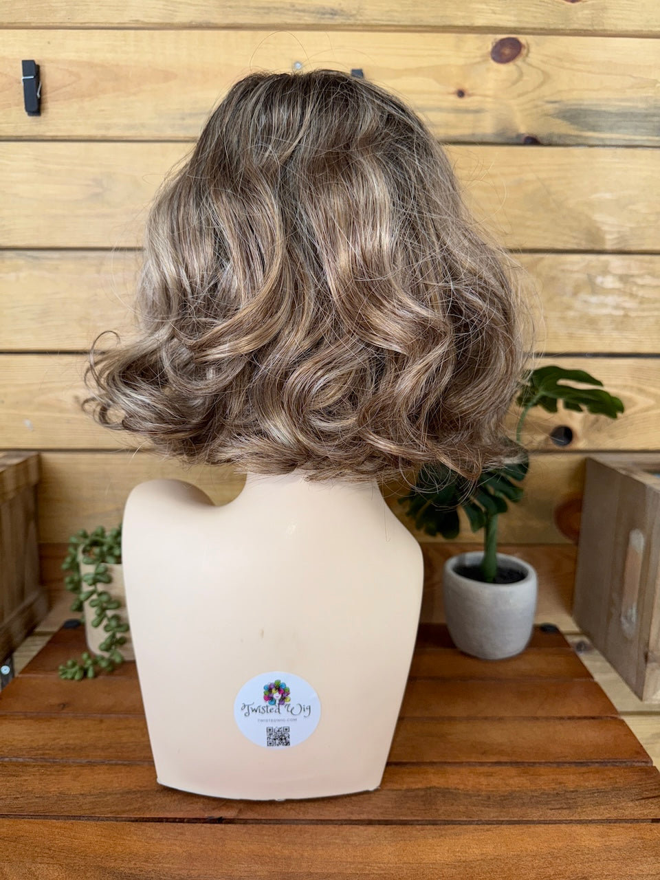 Wavy brown wig on a mannequin head with a wooden background