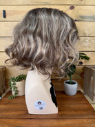 Gray wig on a mannequin head with a wooden background