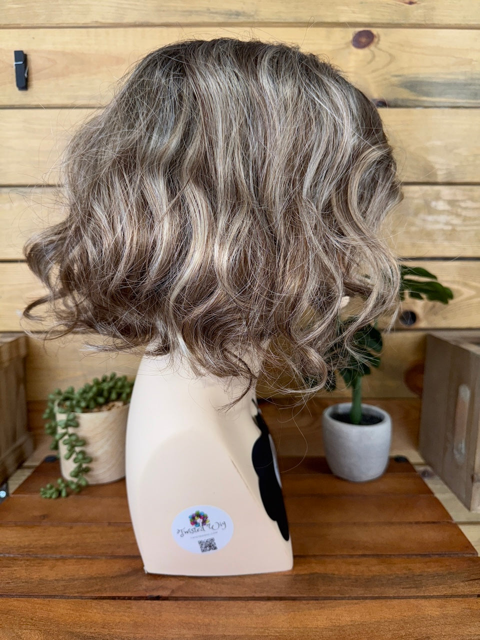Gray wig on a mannequin head with a wooden background