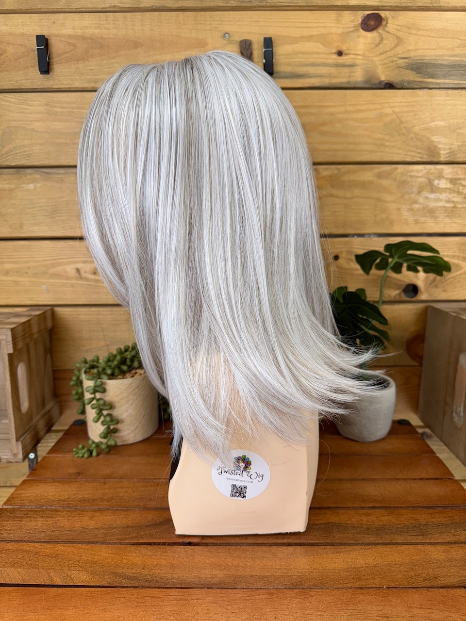 Silver wig on a mannequin head with a wooden background