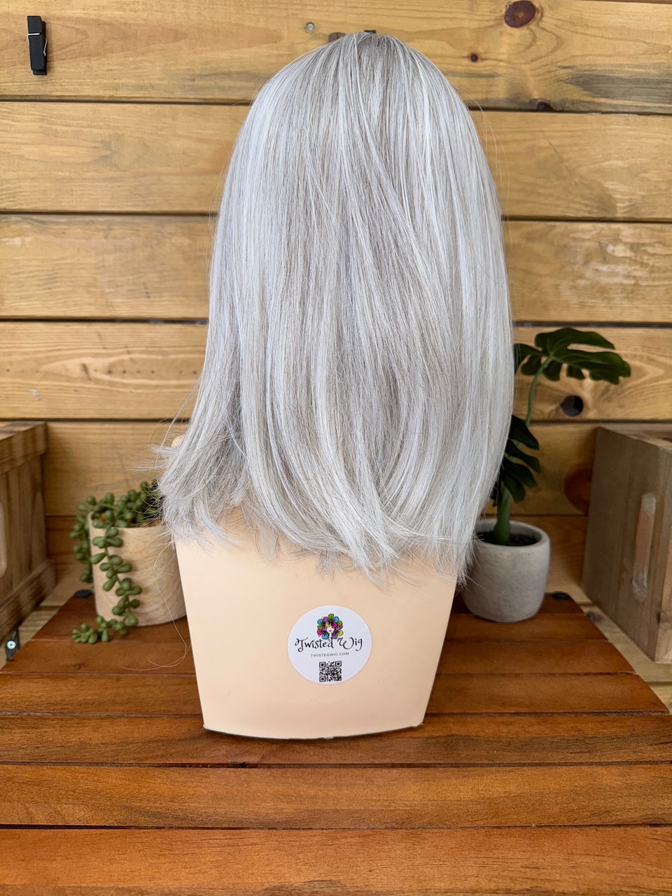 Silver wig on a mannequin head with a wooden background