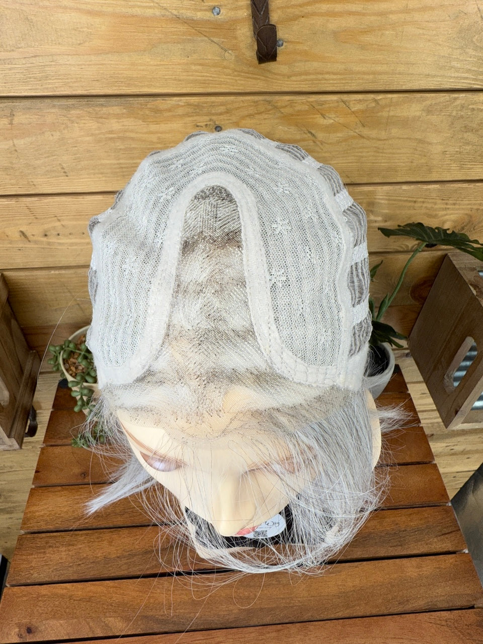 Mannequin head with a white wig on a wooden surface