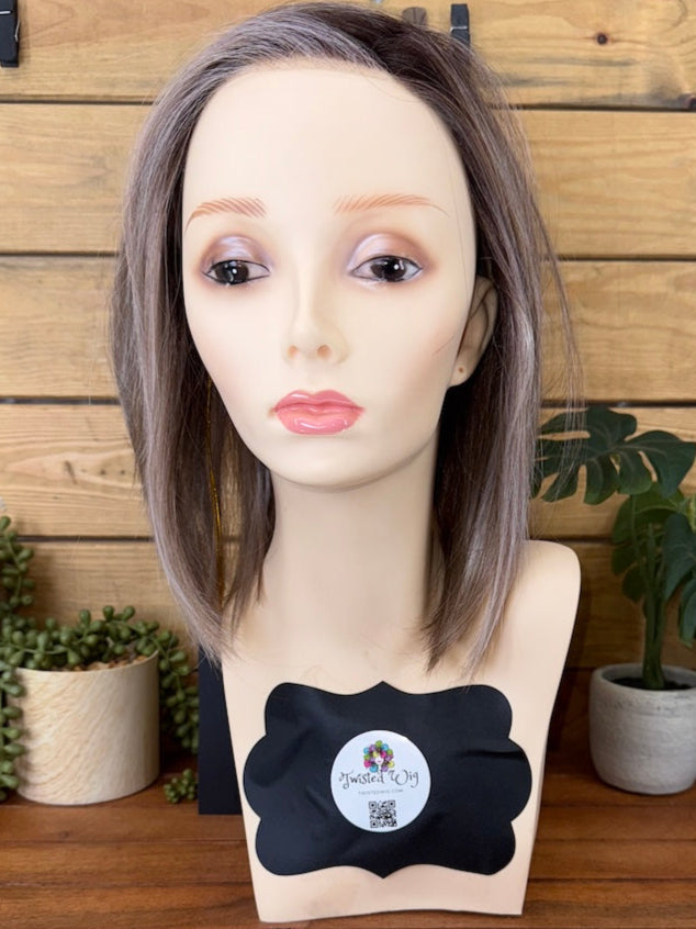 Mannequin head with gray wig on a wooden table against a wooden wall.