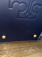 Navy blue leather wallet with gold studs on a wooden surface
